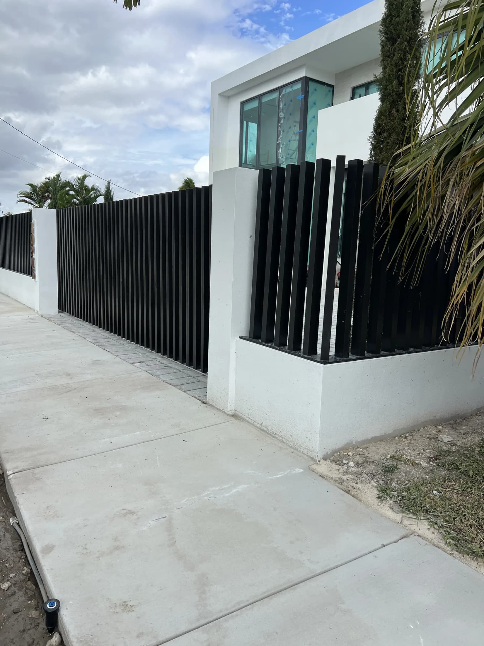 White horizontal aluminum fence along a residential driveway